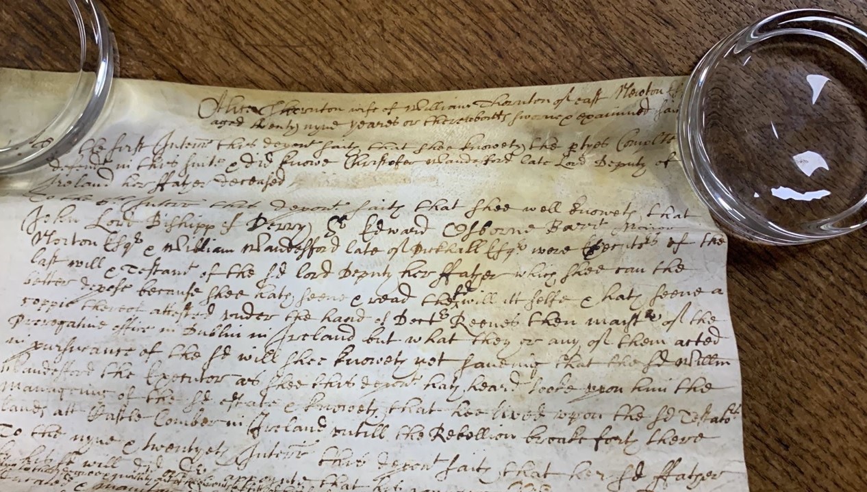 The top of a roll of a parchment document, laid flat with weights
